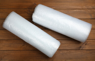 Bubble wrap rolls on wooden background, flat lay