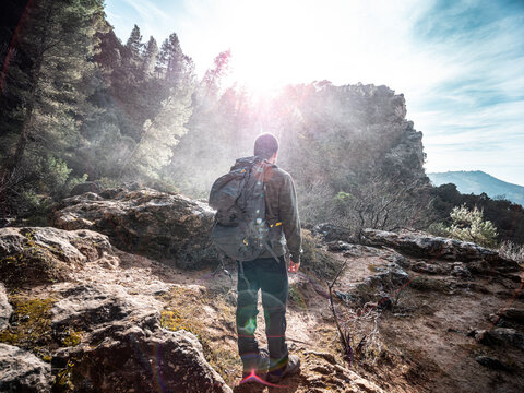 Joven aventurero camina por la naturaleza entre lluvia y rayos de sol