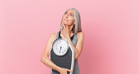 middle age white hair woman holding a weight scale. fitness and diet concept