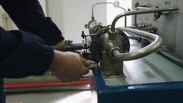 A worker screws the nuts on the hydraulic test bench with the keys. Close-up of a worker's hands