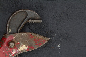 Old adjustable wrench on rusty metal sheet. Sliding forged wrench against a dark industrial background