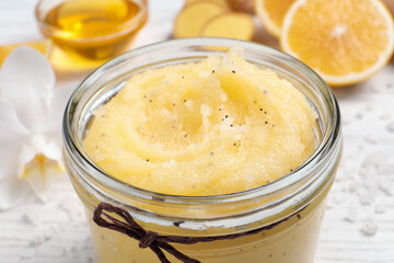 Body scrub in glass jar on white table, closeup