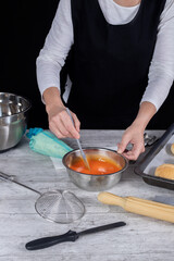 Pastry woman hands stirring yolk glaze on freshly baked dessert processing table. Photography blog and social media. Selective focus