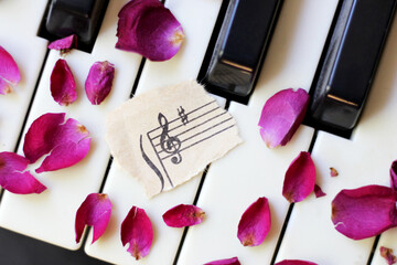 Obraz na płótnie Canvas Musical key and rose petals on the piano