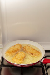 Pan with oil preparing fried bread with egg and flour (Torrijas). Typical Spanish Easter sweet. Traditional home cooking concept. Vertical photography and selective focus