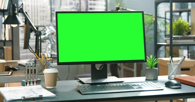 Green screen laptop computer standing at the work desk next to a desk lamp at the modern creative office. Footage shot. Green screen concept