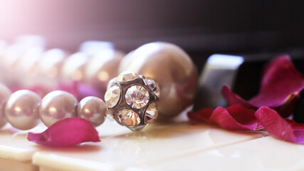 Pearl bracelet with rhinestones and rose petals on the piano