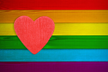 On a wooden textured background of rainbow-colored boards of the LGBT sign is a red heart.It can be used as a border of pride of the gay and lesbian community,for the design of leaflets,greeting cards