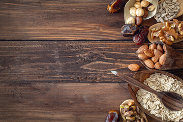 Variety of grains and mixed nuts in organic plates, on wooden brown background , top view with copy space