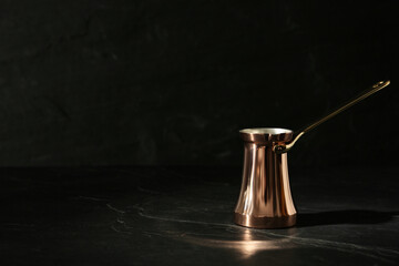 Obraz na płótnie Canvas Beautiful copper turkish coffee pot on black table. Space for text