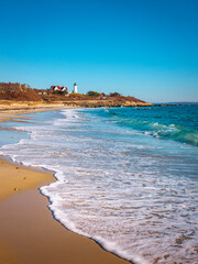 Blue Ocean Seascape with long white foamy waves washing up on the beach near Nobska Lighthouse in Woods Hole on Cape Cod
