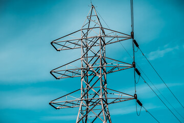 Silhouette effect of high voltage electric towers with electricity transmission power lines, located near riverside and sunset sky background	