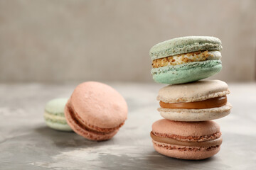 Fototapeta na wymiar Different delicious macarons on light grey table. Space for text