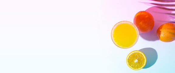 glass with fresh juice, oranges and a leaf of a palm tree on a light background. Added a gradient. Top view, flat lay. Banner