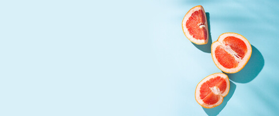 cut halves of grapefruit on a blue background. Top view, flat lay. Banner