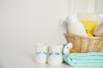 Baby booties and accessories on white table against light background. Space for text