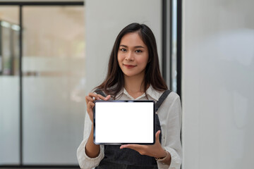 Fototapeta na wymiar Asian businesswoman standing holding tablet blank white screen. Looking at the camera.
