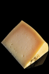 Portion of cured manchego cheese on black background. Vertical shot