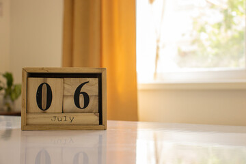 Wooden blocks of the calendar represents the date 6 and the month of July on the background of a...