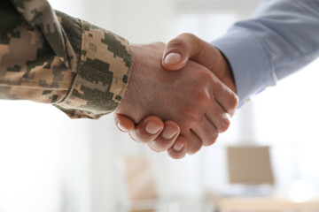 Soldier and businessman shaking hands indoors, closeup - obrazy, fototapety, plakaty