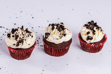 chocolate cupcakes with vanilla cream and pieces of chocolate cookie. on white background Horizontal shot