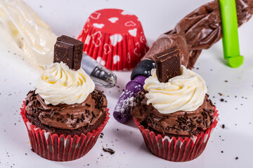 chocolate cupcakes, cream and chocolate topping on white background. Horizontal shot
