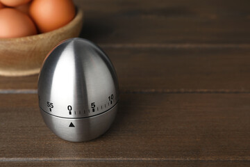Kitchen timer and eggs on wooden table. Space for text