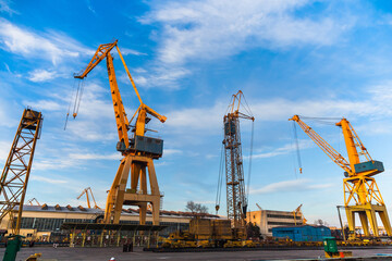 Port cranes on the territory of the seaport in Constanta Romania with blue sky and white clouds. Territory of the seaport with cranes.