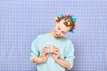Woman with skincare product on face, with bright hair curlers on head