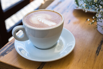 White cup with cappuccino coffee on a wooden table at cafe restaurant terrace. Delicious, aromatic coffee to start a successful day.  