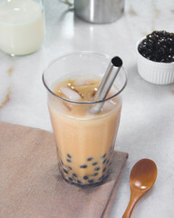 A cup of milk tea with pearls with a metal straw
