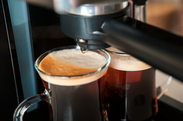 Two transparent cups coffee close-up front view. Home coffee maker and process of making coffee drink. Copy space.
