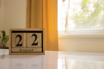 Wooden blocks of the calendar represents the date 22 and the month of August on the background of a...
