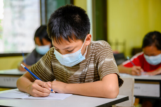 Asian Elementary School Students Wearing A Mask To Prevent Coronavirus (COVID 19) Doing Education In A Classroom At A Rural School On The First Day Of Semester.