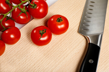 Petites tomates et couteau sur planche en bois