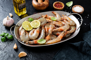 Fresh raw shrimp marinated with spices and lime juice, ready to roast. Black background.