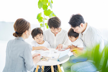 スーツ姿の女性からインテリアの説明を受ける家族