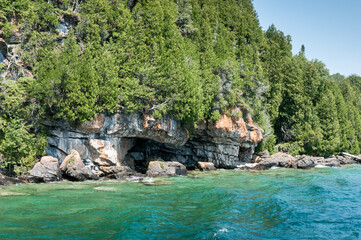 Fototapeta na wymiar Trees with rocks on an island surrounded by blue, aqua, and clear water in Bruce Peninsula, Ontario, Canada.