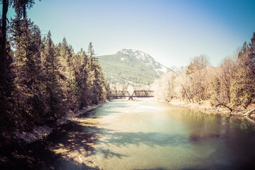 A bridge over the South Fork Skykomish River in Washing State with mountains in the background.