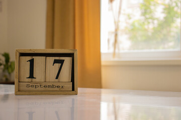 Wooden blocks of the calendar represents the date 17 and the month of September on the background...