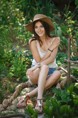 Beautiful young woman gardening outside in summer nature