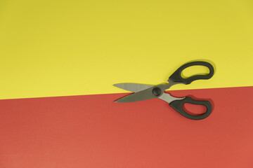 Scissors cut a red-yellow background  cardboard