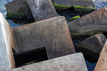 Square stones of breakwaters and the surface of water sea.