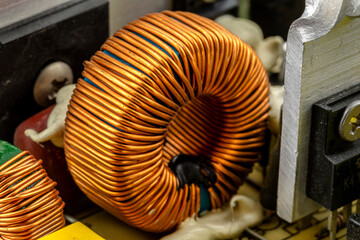 An inductor, toroidal coil on a ring with visible copper scroll, wound on a magnetic coil.