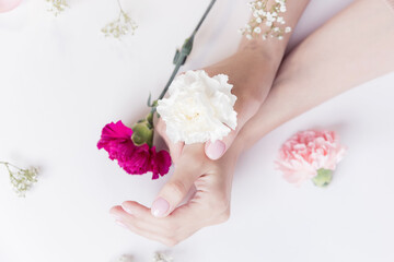 Fototapeta na wymiar Concept beauty skin care. Beautiful stylish trendy female pink manicure with flower on background, top view
