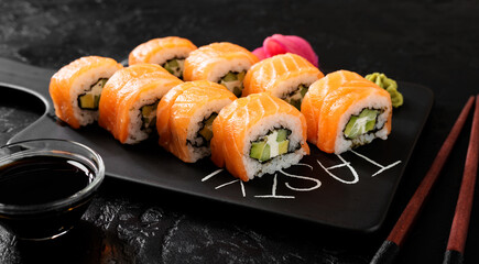 Traditional sushi - Philadelphia with salmon, cucumber avocado and cream cheese. Japanese cuisine. Top view. Black background.