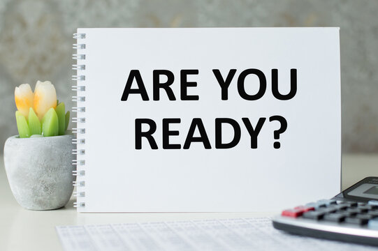 Are You Ready Text written on notebook page on the table next to a calculator, financial statements and a flower in a pot. Motivational Concept image