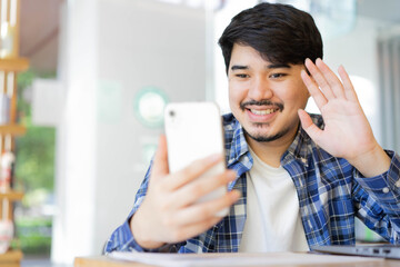close up young middle eastern man sitting at the coffee cafe and using video call form smartphone to talking with friends and family for new normal and healthy lifestyle concept