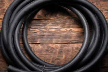 Old rubber water hose on the brown wooden floor background.