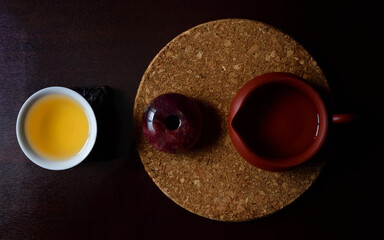 Still life and on top shot of a Chinese clay teapot, a round stone and a teacup, on a cork plate and a brown table